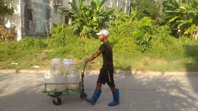 Un cubano lleva porrones para recoger agua en Santiago de Cuba.