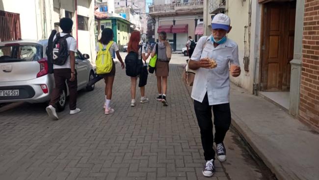 Un hombre con un pan y una bebida en una calle de La Habana.