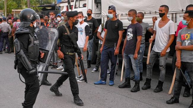 Jóvenes reclutas armados de estacas y tonfas durante la represión del 11J.