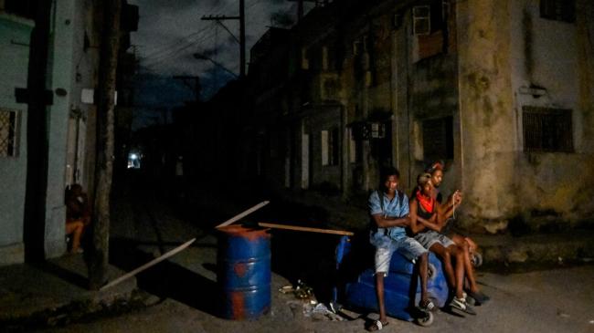 Cubanos sentados en la calle durante un apagón.