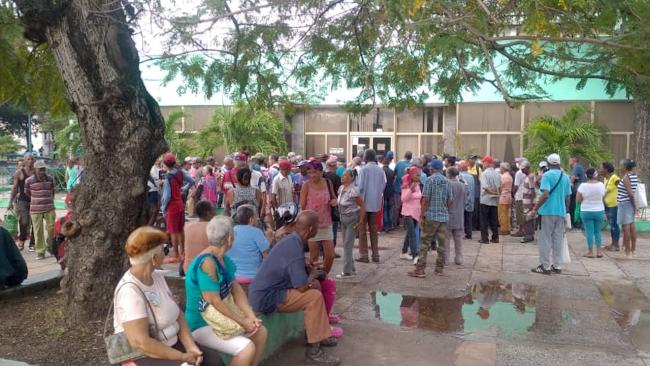 Jubilados esperando para cobrar fuera de una sucursal bancaria.