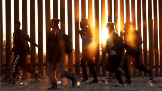 Emigrantes caminan junto al muro en la frontera de EEUU y México en Lukeville, Arizona.