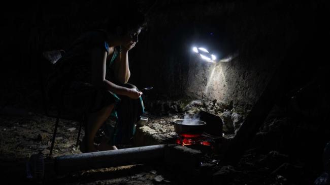 Una cubana cocinando con carbón en medio de un apagón.