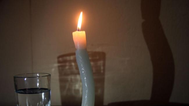 Una vela y vaso de agua en una mesa cubana en apagón.