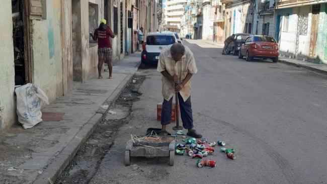 Un anciano recolecta latas para venderlas como materia prima.