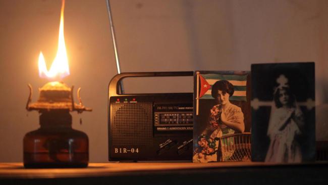 Un quinqué encendido junto a un radio receptor durante un apagón en Cuba.