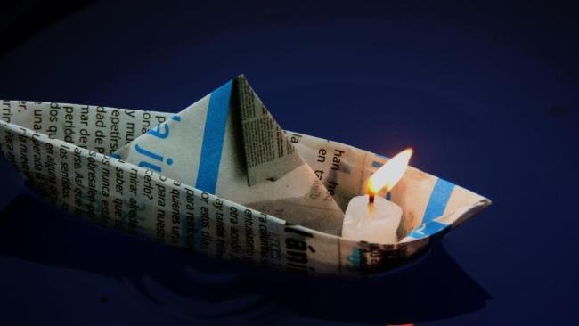 Una vela encendida en un barquito de papel.