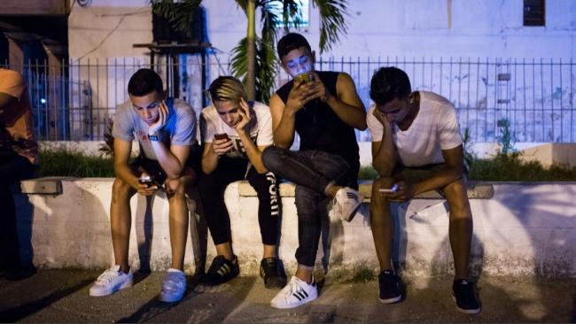 Jóvenes cubanos conectados a internet desde sus teléfonos móviles.