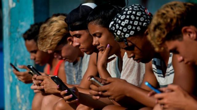 Jóvenes cubanos conectados a internet desde sus teléfonos móviles.