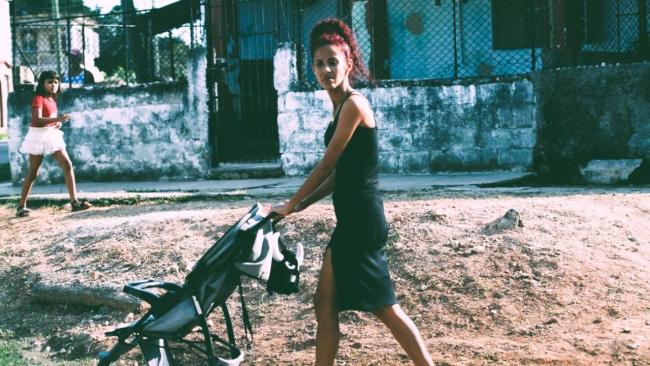 Una mujer cubana con un coche vacío camina por La Habana.
