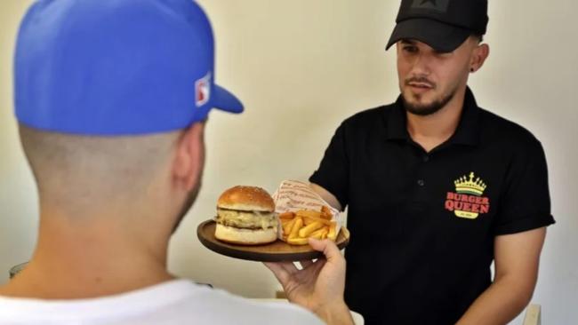 Un trabajador de la cafetería Burguer Queen atendiendo a una persona, en La Habana.