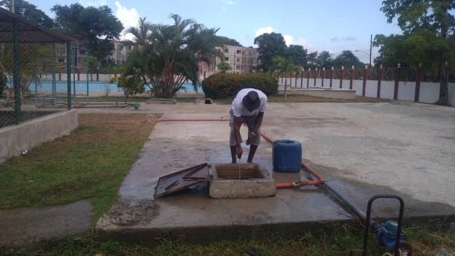 Sacando agua de la cisterna de una piscina olímpica, Santiago de Cuba.