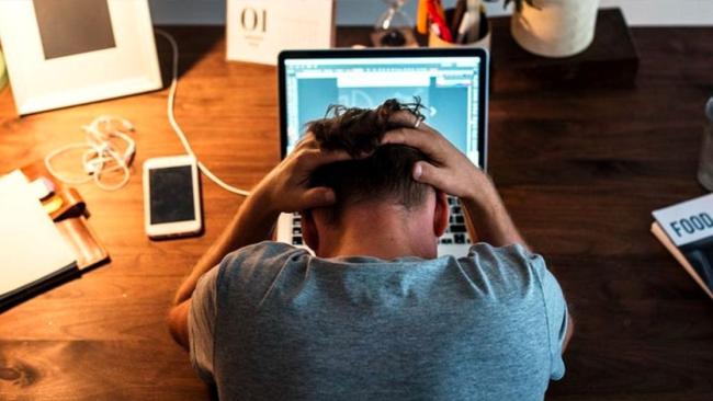 Un hombre estresado delante de su laptop.