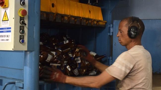Un operario de una prensa de envases de cervezas.