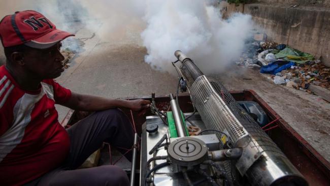 Un trabajador de la fumigación en Matanzas y un basurero al fondo.