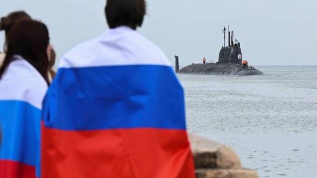 Personas con banderas de Rusia reciben al submarino Kazán en La Habana.