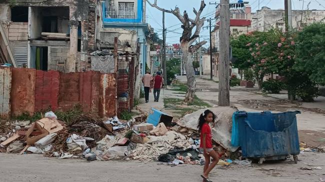 Una niña pasa frente a un basurero en La Habana.