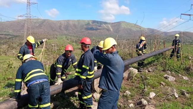 Linieros levantan un poste en una zona afectada por Melissa.