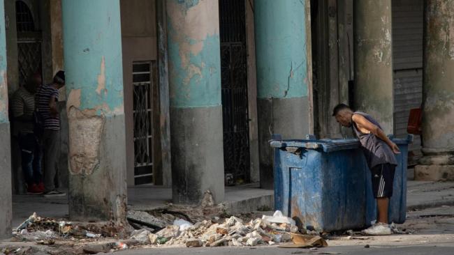 Un hombre revisa la basura en La Habana.