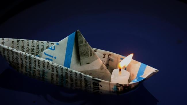 Una vela prendida en un barquito de papel.