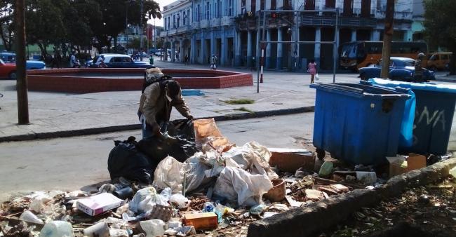 Un hombre escarbando en la basura en La Habana.