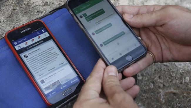 Un cubano consulta redes sociales en sus móviles.