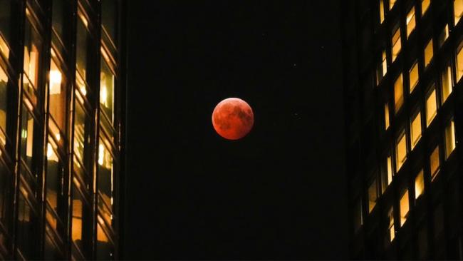 Luna roja entre dos edificios.