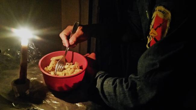 Una persona come a la luz de una vela.