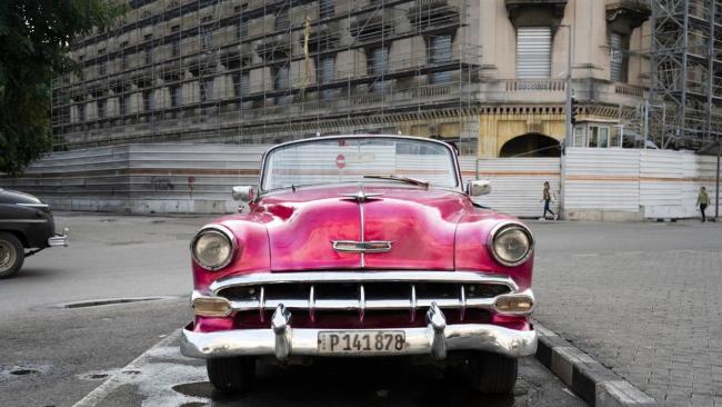 Un carro de época frente a un hotel en construcción en La Habana.