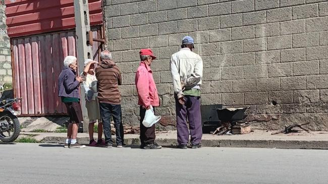 Ancianos cubanos cocinan una caldosa en la calle.