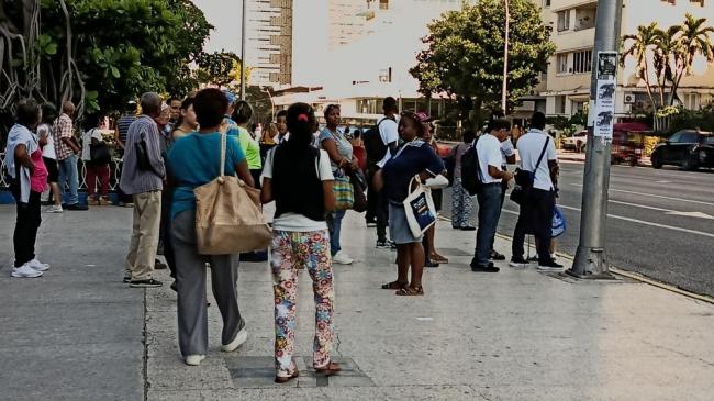 Personas a la espera de un transporte en la parada del Coppelia del Vedado.