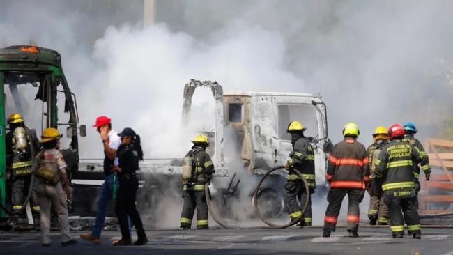Bomberos de Guadalajara intentan apagar un vehículo incendiado por el crimen organizado en aparente retaliación por operativos contra El Mencho, este 22 de febrero, en Guadalajara.