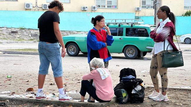 Una anciana enferma y sus familiares esperan transporte frente a un hospital de Camagüey.