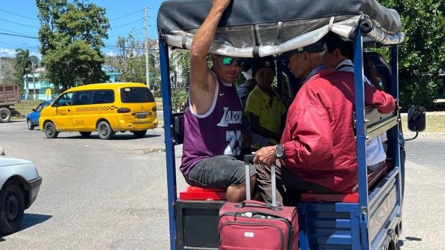 Personas en un triciclo eléctrico en La Habana.