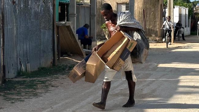 Un hombre descalzo recoge cajas de cartón en Camagüey.