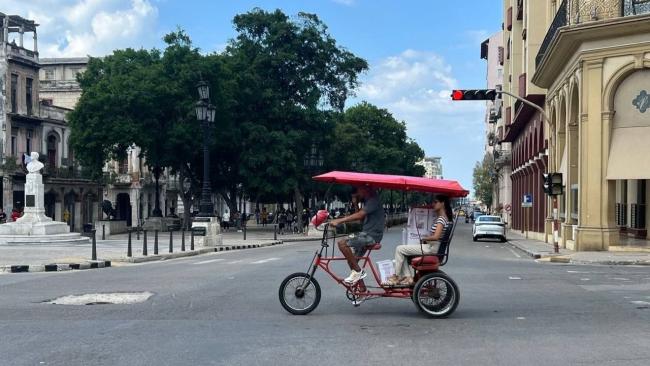 Un bicitaxi lleva a una mujer y su compra.
