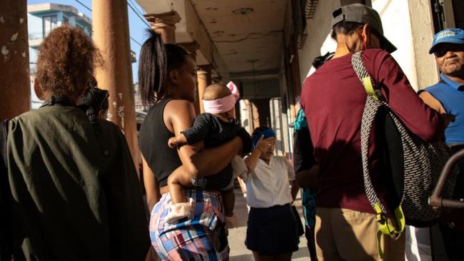 Una madre cubana con su bebé en una cola en La Habana.