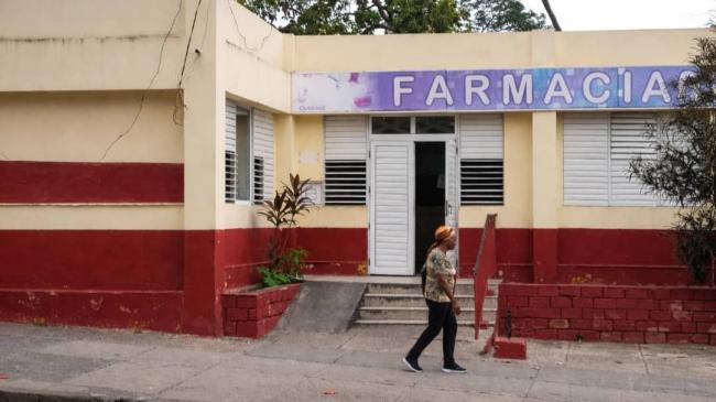 Una mujer frente a una farmacia en Santiago de Cuba.