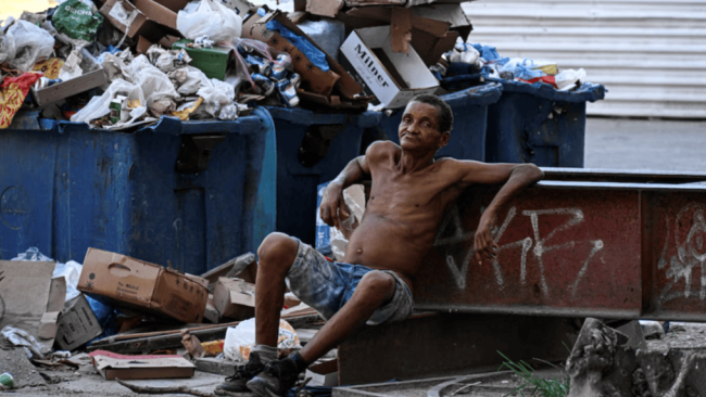 Un hombre junto a depósitos de basura en La Habana.