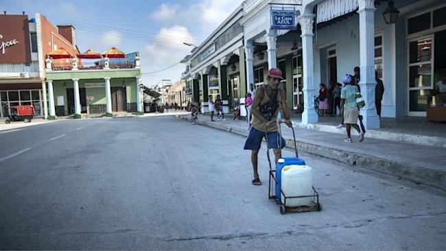 Un hombre carga agua ante la falta de suministro. 