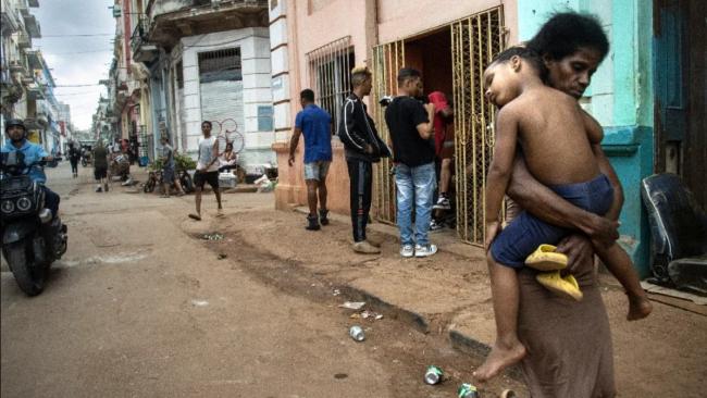 Una madre carga a su hijo en una calle de La Habana.