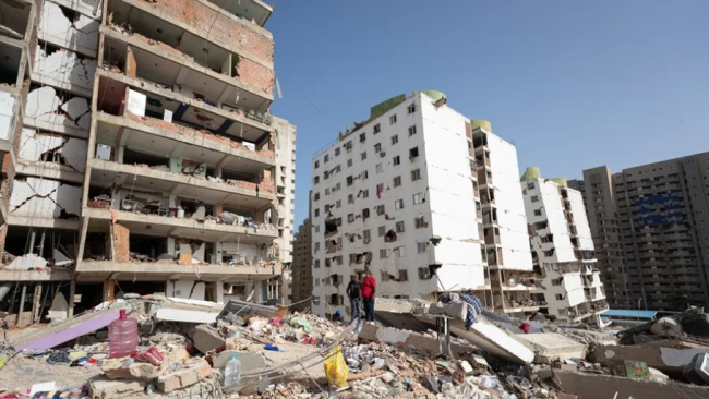 Personas caminan entre escombros de edificios afectados en Catia La Mar, La Guaira.