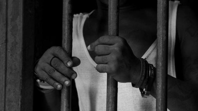 Un hombre tras las rejas en una cárcel.