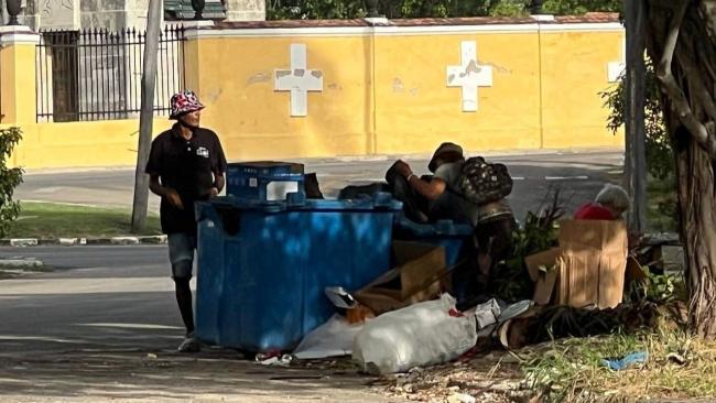 Tres personas buscan en la basura cerca del cementerio de Colón en La Habana.
