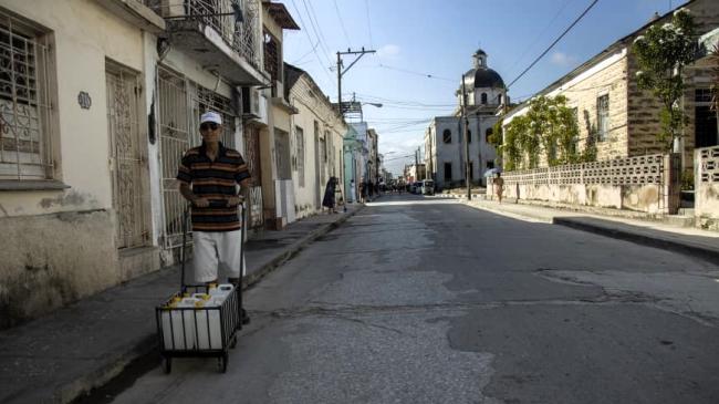 Un hombre carga con bidones de agua.