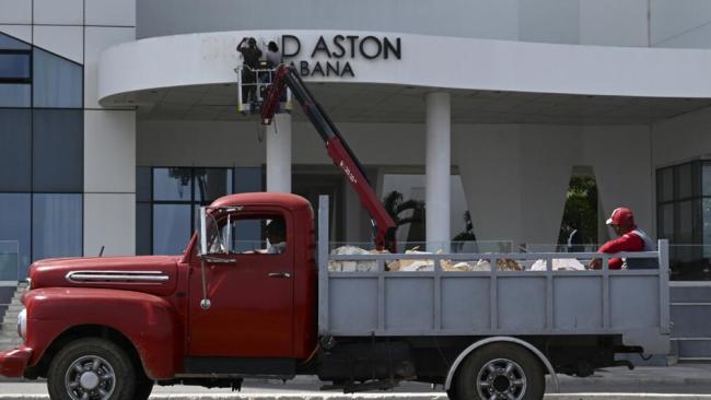 Trabajadores desmontan el letrero a la entrada de un hotel de La Habana.
