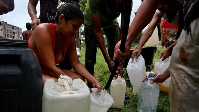 Vecinos de una comunidad llenan vasijas con el agua de una pipa.