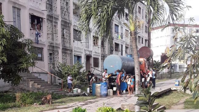 Cubanos cargan agua de una pipa.