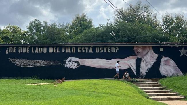 Jóvenes ante un mural de propaganda política en La Habana.
