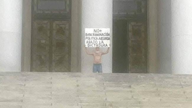 El individuo sosteniendo un cartel en la entrada del Capitolio habanero.